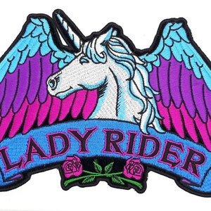 May include: Embroidered patch featuring a white unicorn with a blue and pink gradient winged design. The unicorn is facing left and has a horn. The patch has a blue banner with the text "LADY RIDER" in black and pink lettering. The banner is decorated with two pink roses.