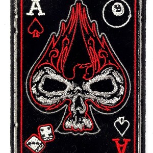 May include: Embroidered patch featuring a skull with flames, a playing card ace of spades, dice, and a black 8 ball. The patch is black with red and silver embroidery.