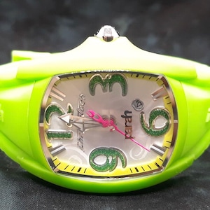 May include: A green wristwatch with a white face and green glitter accents. The watch face has the words "yber" and "Chrono Tech" printed on it.