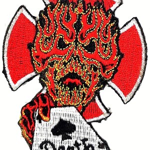 May include: Embroidered patch featuring a red and yellow skull with flames, holding a white playing card with a black spade and the word "Aces" written on it. The skull is surrounded by a red cross with white trim.