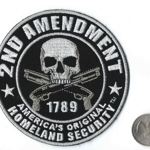 May include: A black and white embroidered patch with a skull and crossbones, two pistols, and the text "2nd Amendment, America's Original Homeland Security, 1789".