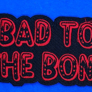 May include: Red embroidered patch with the words "Bad to the Bone" on a black background.