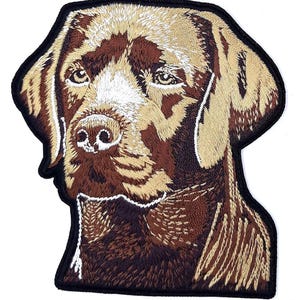 May include: Embroidered patch featuring a detailed portrait of a Labrador Retriever dog. The patch showcases the dog's head and upper chest, with brown, tan, and white thread on a black border. The dog's eyes and nose are clearly defined.