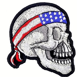 May include: Embroidered patch of a white skull wearing a red, white, and blue bandana with stars. The bandana is tied around the skull's head.
