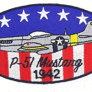 May include: An oval-shaped embroidered patch with a gray and yellow P-51 Mustang airplane flying over a red and white striped American flag. The text "P-51 Mustang 1942" is embroidered below the airplane.