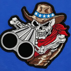 May include: Embroidered patch featuring a skeleton wearing a cowboy hat with a red bandana and holding a double-barreled shotgun. The hat has a band with white stars on it.