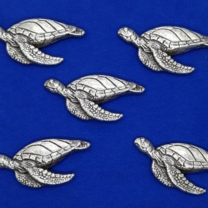 May include: Five silver turtle figurines on a blue background. The turtles are facing different directions and have detailed features.