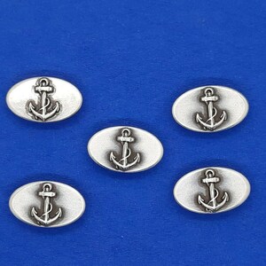 May include: Five silver oval-shaped buttons with an anchor design. The anchors are raised and have a detailed design.