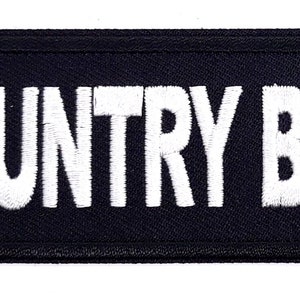May include: Black embroidered patch with white text that reads "COUNTRY BOY".