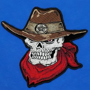 May include: Embroidered patch of a skull wearing a brown cowboy hat with a pentagram on the band and a red bandana.