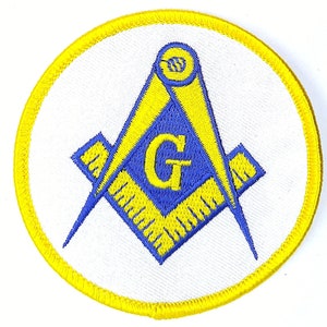 May include: A yellow and blue embroidered patch with a Masonic symbol, a square and compass, on a white background.