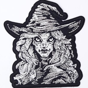 May include: Black and white embroidered iron-on patch of a witch with a pointed hat and long hair.