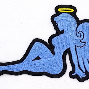 May include: Blue embroidered patch of a woman with wings and a halo. The woman is lying down with her wings spread out behind her.