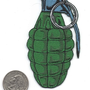 May include: Embroidered patch of a green hand grenade with a blue top and a silver pull ring. The patch is next to a United States quarter for size comparison.
