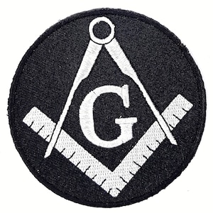 May include: Black and white embroidered patch with a compass and square, a 'G' in the center, and a white border.