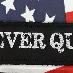 May include: Black patch with white embroidered text that reads "NEVER QUIT."