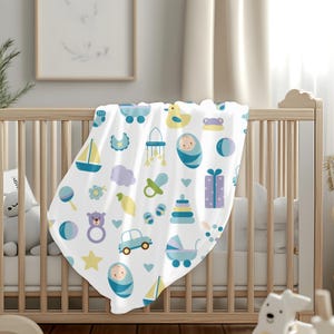 K&ouml;nnte beinhalten: Eine wei&szlig;e Babydecke mit einem blauen und gelben Muster aus Babyspielzeug, darunter eine Rassel, ein Segelboot, ein Schnuller, ein Spielzeugauto, ein Teddyb&auml;r, eine Babyflasche, ein Stern, eine Wolke, eine Geschenkbox, ein Babymobil, ein Ball, ein Baby im Bettchen und eine Ente.