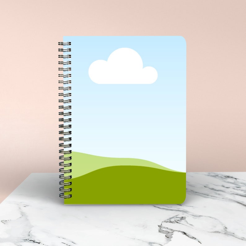 May include: A spiral bound notebook with a blue sky and green grass design. The cover features a white cloud.