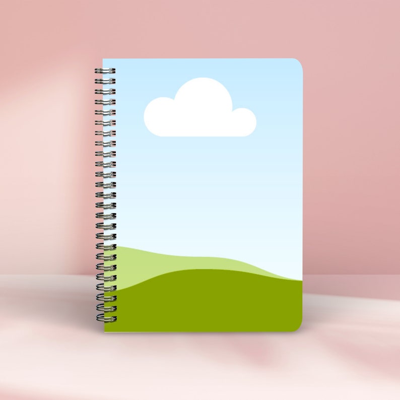 May include: A blue and green spiral bound notebook with a white cloud and a green hill design.