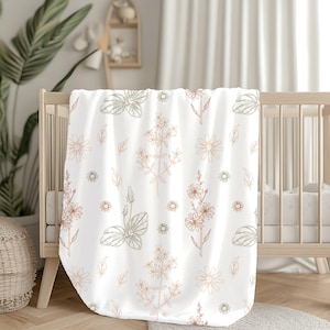 May include: A white baby blanket with a floral pattern in shades of brown and green. The blanket features a repeating pattern of flowers, leaves, and stems.