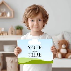 May include: A rectangular sign featuring a light blue sky background with a single white cloud at the top and a green rolling hill at the bottom. The centre of the sign displays the black text "YOUR design HERE" in a clear, bold serif font.