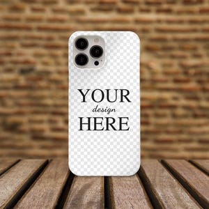 May include: White iPhone case with a clear back and a black camera bump. The text "YOUR design HERE" is printed on the case.