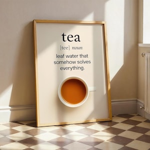 May include: A framed print with the definition of "tea" in black text. The definition reads "leaf water that somehow solves everything." A white teacup filled with tea is at the bottom of the print. The frame is a light brown colour.