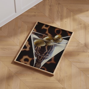 May include: A close-up of a martini glass filled with a clear liquid and three green olives. The glass is on a black and brown patterned background.