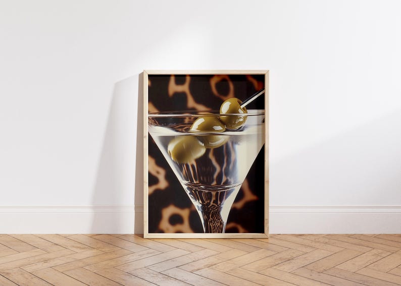 May include: A framed print of a martini glass with green olives, set against a brown and black animal print background.