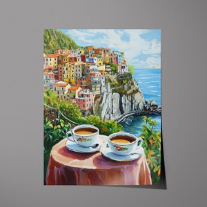 May include: Two cups of coffee on a table with a red tablecloth, overlooking a colorful Italian village built on a cliffside with a blue ocean in the background.