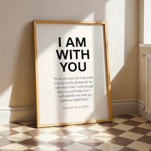 Könnte beinhalten: Ein gerahmter Druck mit dem Text "I AM WITH YOU" in großen schwarzen Buchstaben. Darunter ist ein Bibelvers aus Jesaja 41,10 in kleinerer Schrift gedruckt. Der Rahmen ist hellbraun, der Hintergrund weiß.