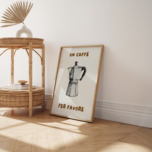 May include: A framed print with a white background and brown text that reads "Un Caffe Per Favore". The print features a black and white illustration of a traditional Italian coffee pot.