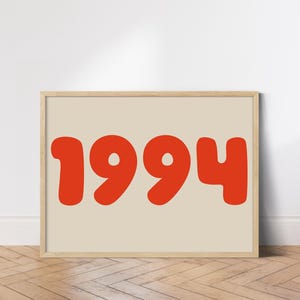 May include: A beige framed print with the year 1994 in large, red, rounded font.