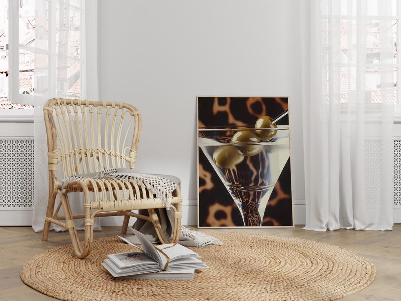May include: A wicker chair with a woven seat and back sits on a jute rug in front of a white wall. A framed print of a martini glass with olives hangs on the wall.