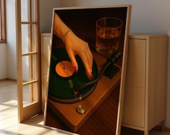 May include: A framed print featuring a vintage record player with a green vinyl record. A hand with red nail polish is poised over the record. A glass of amber liquid sits nearby. The record player is made of wood.