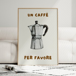 May include: A white poster with brown text that reads "UN CAFFE' PER FAVORE". A black and white illustration of a coffee pot is in the center of the poster.