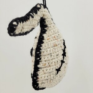 May include: A crocheted white and black ornament shaped like a bird with a black string for hanging.