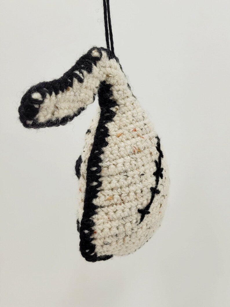May include: A crocheted white and black ornament shaped like a bird with a black string for hanging.