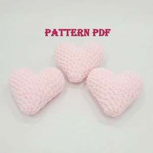 May include: Three pink crocheted hearts on a white background. The text "PATTERN PDF" is written in red at the top of the image.