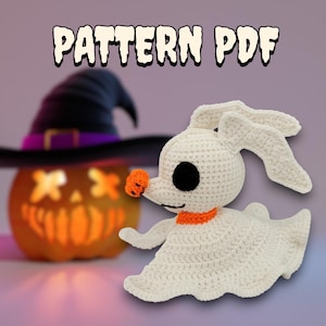 May include: A crocheted white ghost-like character with black eyes, an orange nose, and an orange collar. The image also features a carved pumpkin and a witch's hat. The text "PATTERN PDF" is at the top.