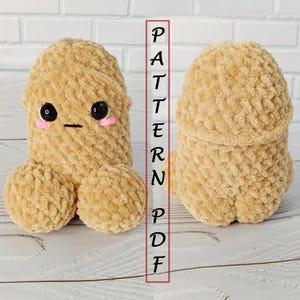 Peut inclure: Une peluche au crochet de couleur beige en forme phallique, avec deux sections de base rondes et un sommet arrondi. L'avant présente des yeux en plastique noir, une bouche brodée droite et des joues roses. Le texte PATTERN PDF est visible.
