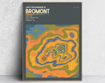May include: A framed topographic map print of Bromont, Quebec, featuring a dark gray background with text including 'CARTE TOPOGRAPHIQUE DE BROMONT', 'ESTRIE, QUÉBEC', 'MASSIF: MONTAGNES VERTES', 'ALTITUDE: 553 M', and 'ÉQUIDISTANCE: 15 M' above a colorful contour map.