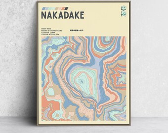May include: A framed art print featuring a colorful topographic map of Mount Nakadake. The artwork displays a layered design in shades of blue, peach, and green, with the mountain's name and elevation details at the top.