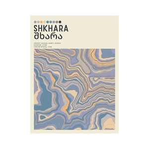 May include: A poster with the text "SHKHARA" in English and Georgian script, above a topographic map design. The map features blue, orange, and gray contour lines. The poster also includes the text "Greater Caucasus, Svaneti, Georgia" and "Elevation: 5,193m".