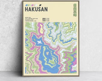 May include: A framed print featuring a topographic map of Mount Haku in Japan. The map uses a palette of blue, green, pink, and yellow to depict elevation contours. The word "HAKUSAN" is printed in bold, black letters at the top.