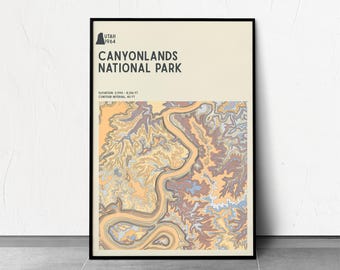 Puede incluir: Un póster enmarcado con un mapa del Parque Nacional Canyonlands, Utah. El póster tiene un marco negro y un fondo crema. El mapa utiliza tonos de naranja, marrón y azul para representar el terreno. El texto en la parte superior dice "Canyonlands National Park".