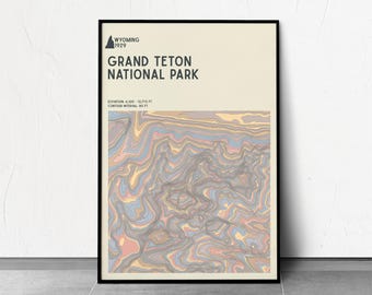 May include: Framed art print of Grand Teton National Park, Wyoming. The print features a topographic map design with a color palette of beige, gray, blue, and peach. The text at the top reads "Wyoming 1929" and "Grand Teton National Park".