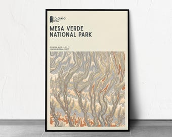 May include: Framed poster featuring a topographic map of Mesa Verde National Park in Colorado. The poster has a black frame and a neutral background. The map uses shades of brown, gray, and orange to depict the park's elevation and contours. Text at the top reads "Mesa Verde National Park."