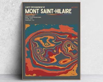 May include: A framed topographic map print of Mont Saint-Hilaire, Quebec, featuring a dark gray background with bold, abstract contour lines in shades of orange, red, and teal. The text reads CARTE TOPOGRAPHIQUE DE MONT SAINT-HILAIRE QC-009.