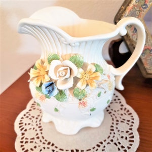 Mały (około 5" wysokości) porcelanowy dzbanek lub dzbanek w kształcie dzbanka z biskwitu z nakładanymi kwiatami biskwitowymi